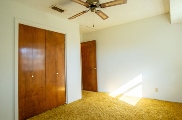 unfurnished bedroom with a textured ceiling, carpet, ceiling fan, and a closet