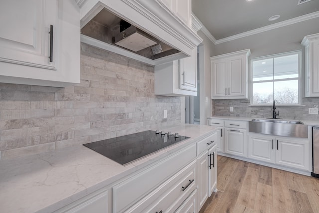 kitchen featuring black electric stovetop, white cabinetry, backsplash, premium range hood, and sink