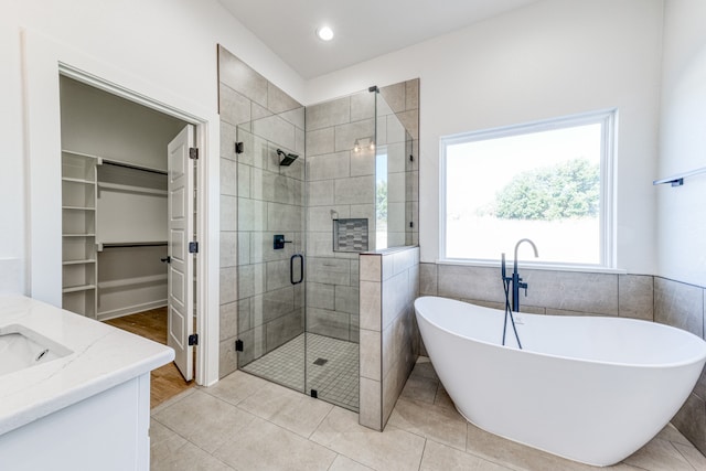 bathroom featuring plus walk in shower, tile patterned flooring, and vanity