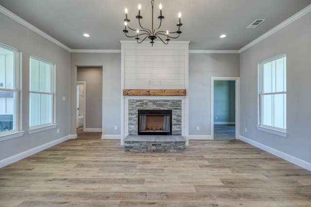 unfurnished living room with light wood-type flooring, a fireplace, ornamental molding, and an inviting chandelier