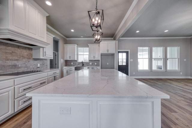 kitchen featuring pendant lighting, light wood-type flooring, a kitchen island, and black electric cooktop