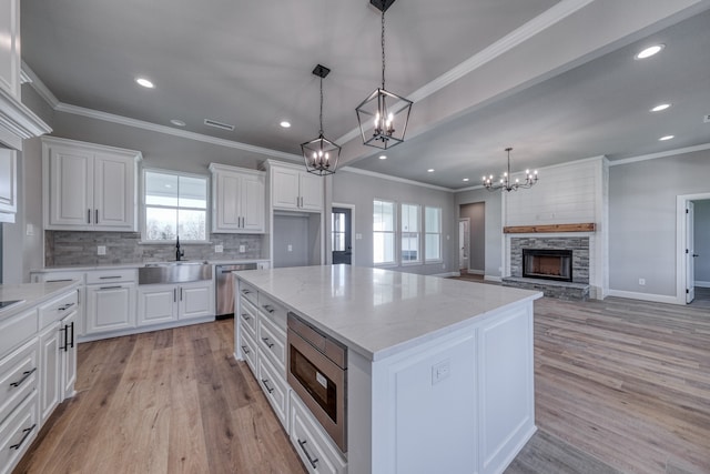 kitchen with light hardwood / wood-style floors, a center island, sink, white cabinets, and a fireplace