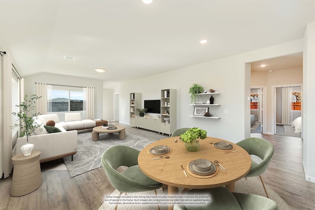 dining area featuring vaulted ceiling and light hardwood / wood-style flooring