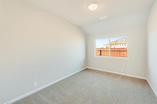 carpeted empty room featuring vaulted ceiling