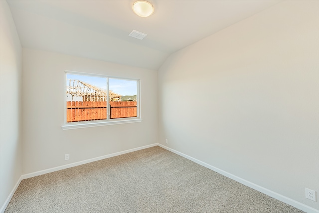 unfurnished room featuring lofted ceiling and carpet