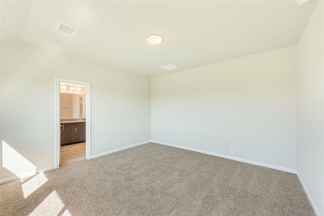 spare room featuring lofted ceiling and light colored carpet