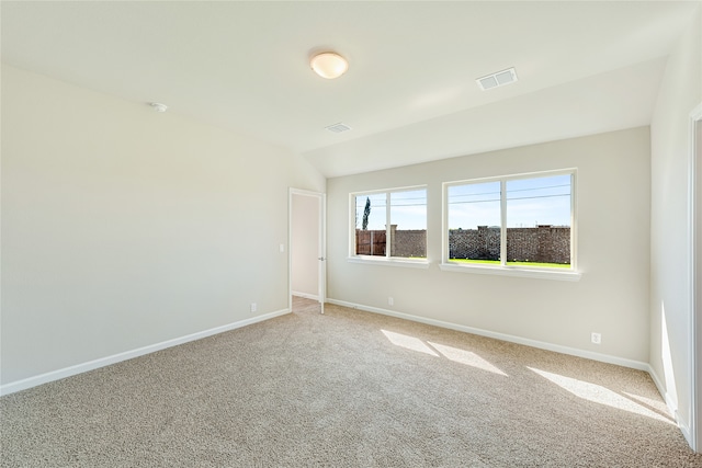 empty room featuring carpet and vaulted ceiling