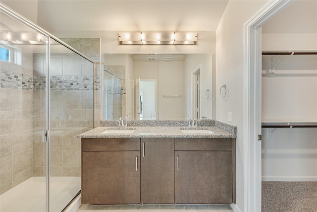 bathroom featuring a shower with door and vanity