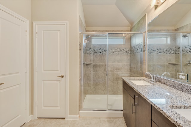 bathroom featuring vanity, lofted ceiling, a shower with door, and tile patterned flooring