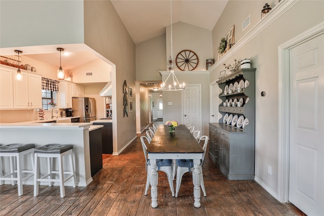 dining space featuring dark hardwood / wood-style floors, sink, high vaulted ceiling, and a chandelier