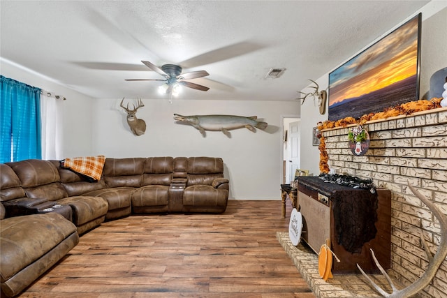 living room with a textured ceiling, light hardwood / wood-style floors, and ceiling fan