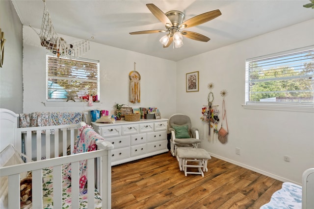 bedroom featuring a crib, ceiling fan, and hardwood / wood-style flooring