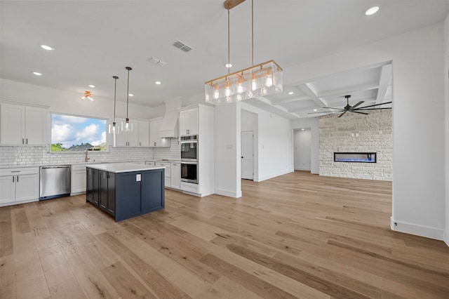 kitchen with light hardwood / wood-style flooring, decorative light fixtures, white cabinetry, stainless steel appliances, and a center island