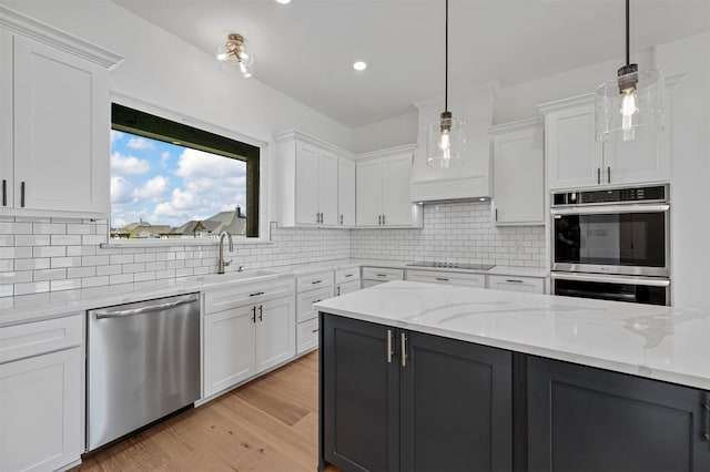 kitchen featuring decorative light fixtures, sink, stainless steel appliances, and white cabinets