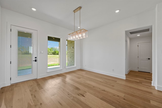 unfurnished dining area featuring an inviting chandelier and light wood-type flooring