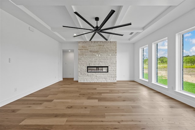 unfurnished living room with beam ceiling, light hardwood / wood-style floors, a fireplace, and ceiling fan