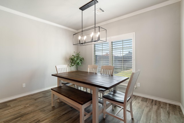 dining room with crown molding, visible vents, a chandelier, wood finished floors, and baseboards