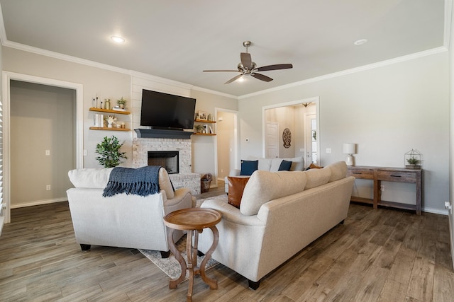 living room with a fireplace, ornamental molding, a ceiling fan, wood finished floors, and baseboards