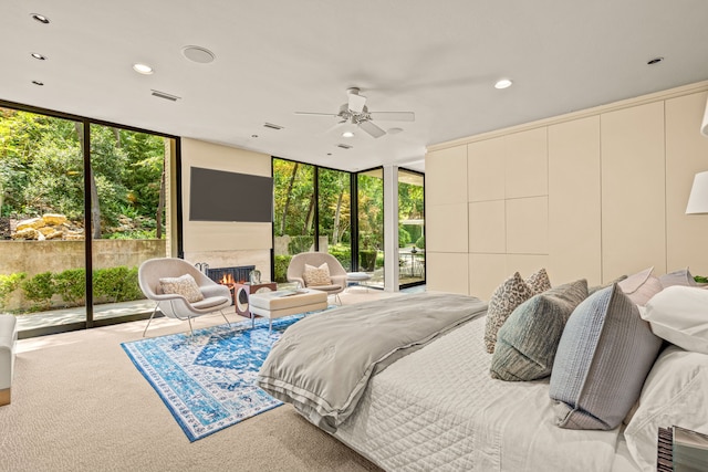 carpeted bedroom featuring expansive windows, visible vents, a lit fireplace, and access to exterior