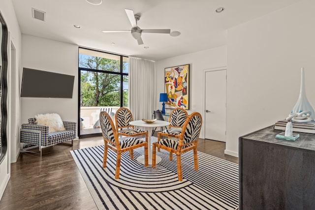 dining space with ceiling fan, a wall of windows, and dark wood-type flooring