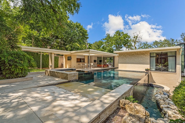 pool with a patio area and an in ground hot tub