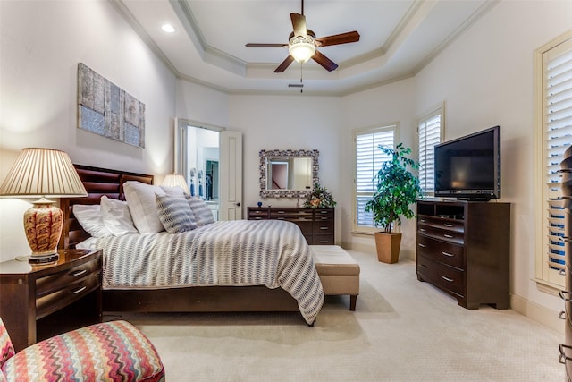 bedroom with ornamental molding, light colored carpet, ceiling fan, and a tray ceiling