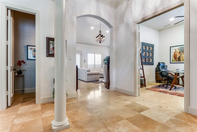 foyer entrance featuring a high ceiling, crown molding, a chandelier, and ornate columns