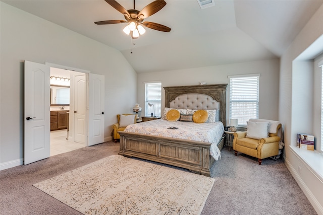 carpeted bedroom featuring multiple windows, connected bathroom, lofted ceiling, and ceiling fan