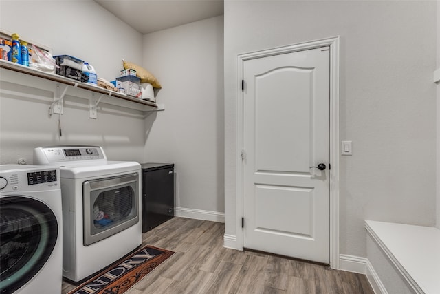 clothes washing area with light hardwood / wood-style floors and washer and dryer