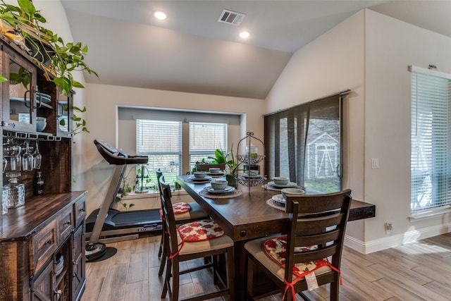 dining room featuring light wood-type flooring and vaulted ceiling