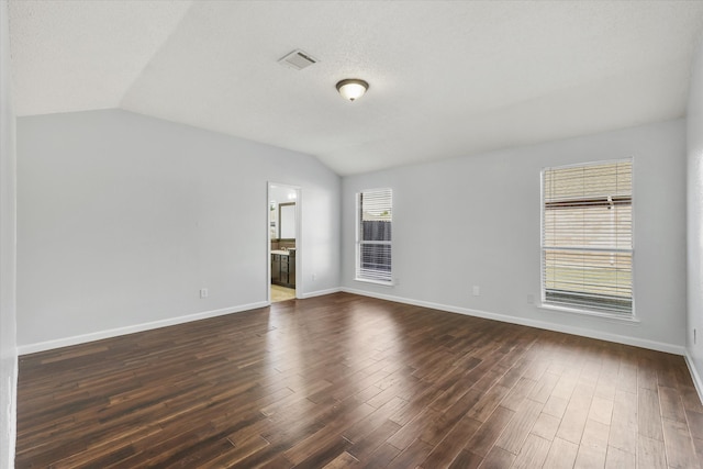 spare room with a wealth of natural light, lofted ceiling, and dark hardwood / wood-style flooring