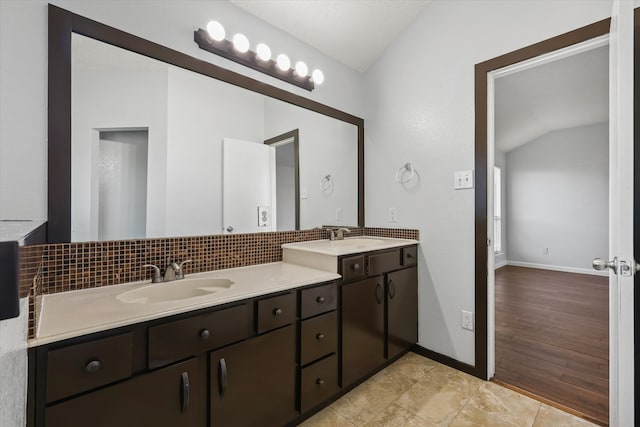 bathroom with vanity, lofted ceiling, hardwood / wood-style floors, and backsplash