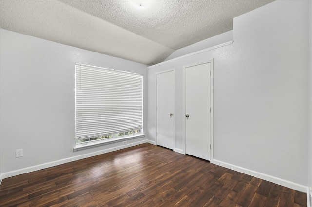 unfurnished bedroom featuring a textured ceiling, vaulted ceiling, and dark wood-type flooring