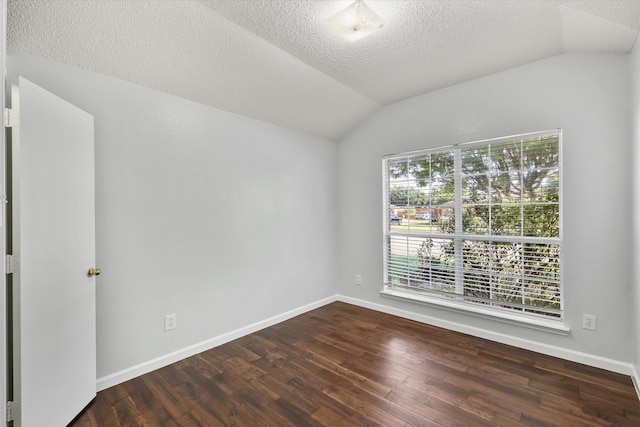 empty room featuring a wealth of natural light, vaulted ceiling, and dark hardwood / wood-style flooring