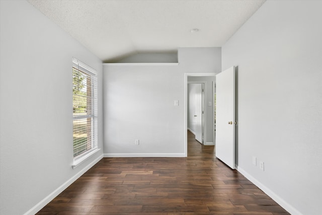 spare room featuring a textured ceiling, lofted ceiling, and dark hardwood / wood-style flooring