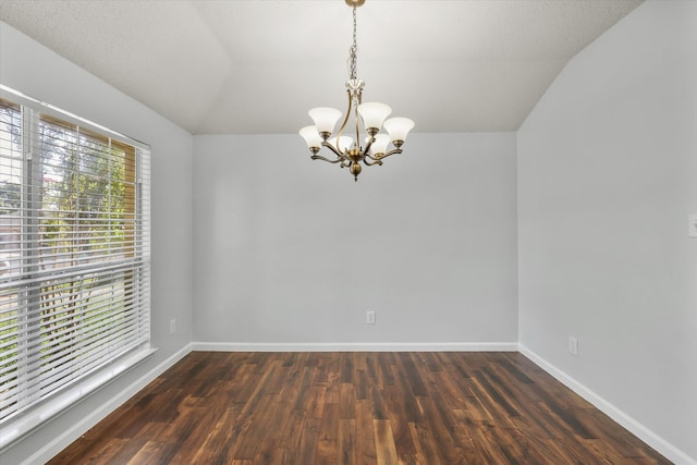 empty room with a notable chandelier, lofted ceiling, dark hardwood / wood-style floors, and a textured ceiling