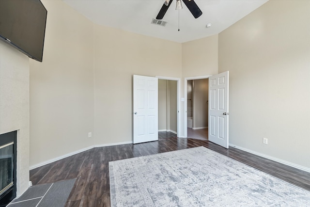 unfurnished bedroom with dark hardwood / wood-style floors, a towering ceiling, and ceiling fan