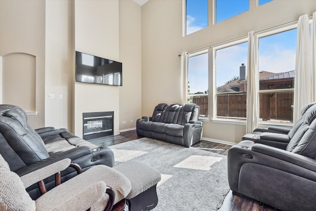 living room featuring a high ceiling, plenty of natural light, and dark wood-type flooring