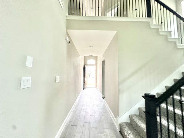 hallway with a towering ceiling and hardwood / wood-style flooring