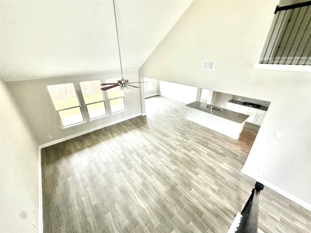 unfurnished living room featuring high vaulted ceiling, light wood-type flooring, and ceiling fan