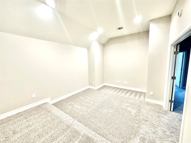 unfurnished room featuring a textured ceiling, carpet flooring, and vaulted ceiling