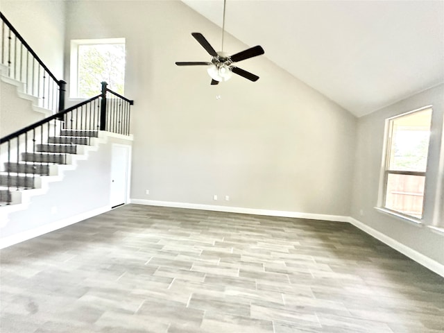 unfurnished living room with ceiling fan, light hardwood / wood-style flooring, plenty of natural light, and high vaulted ceiling