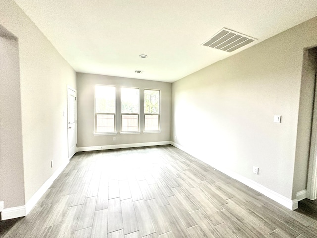 spare room with a textured ceiling and light hardwood / wood-style flooring