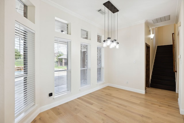 unfurnished dining area with an inviting chandelier, light wood-type flooring, and ornamental molding