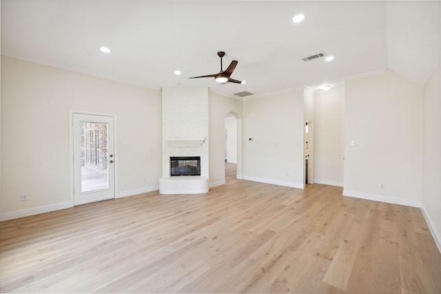 unfurnished living room featuring light hardwood / wood-style floors, ceiling fan, a fireplace, and crown molding