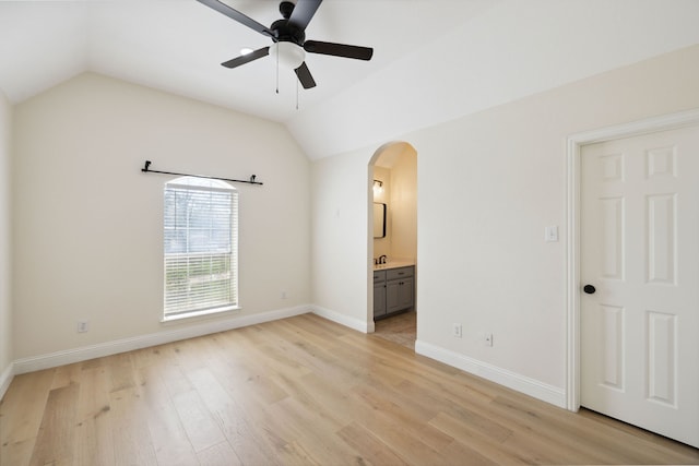 interior space featuring ceiling fan, light wood-type flooring, ensuite bath, and vaulted ceiling