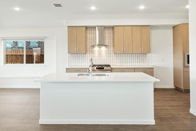 kitchen featuring light brown cabinets, dark hardwood / wood-style floors, wall chimney exhaust hood, and an island with sink