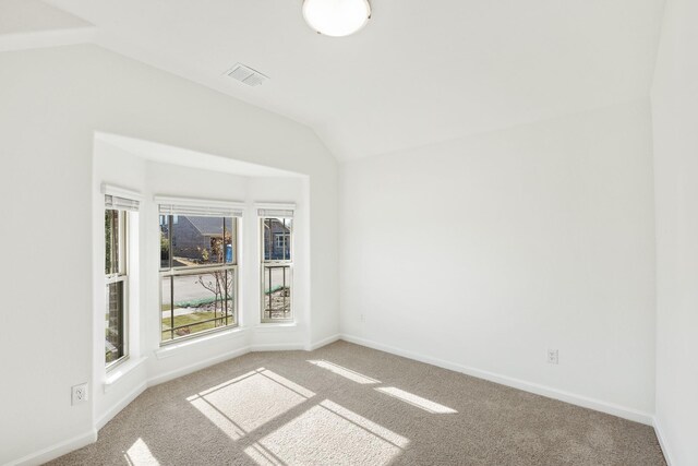 carpeted empty room featuring vaulted ceiling