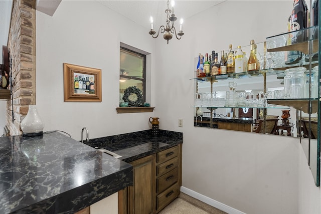 bar featuring dark stone counters and an inviting chandelier