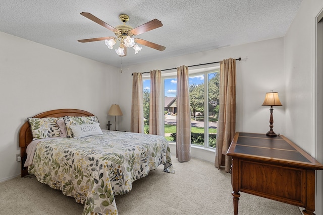 bedroom with ceiling fan, light colored carpet, and a textured ceiling